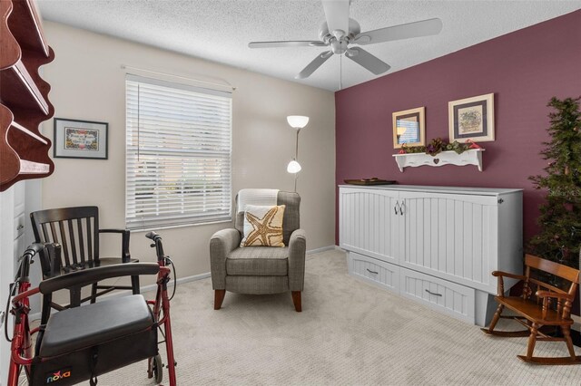 living area with light colored carpet, a textured ceiling, and ceiling fan