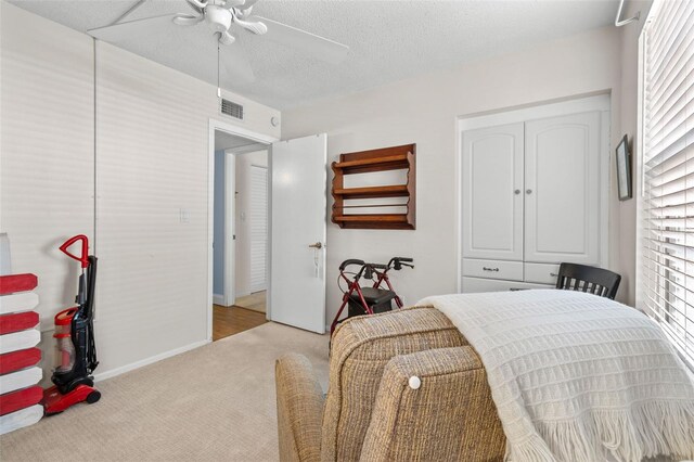 carpeted bedroom with a closet, a textured ceiling, and ceiling fan