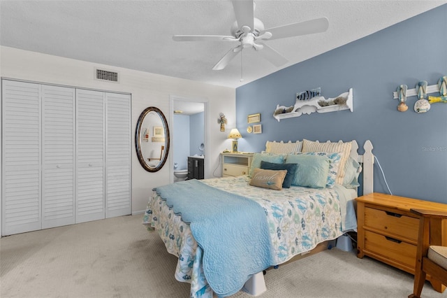 carpeted bedroom with a textured ceiling, ensuite bath, ceiling fan, and a closet