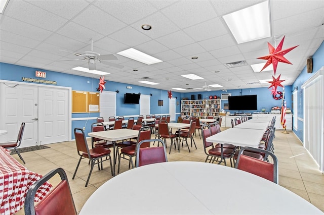 dining space with ceiling fan, light tile patterned floors, and a drop ceiling