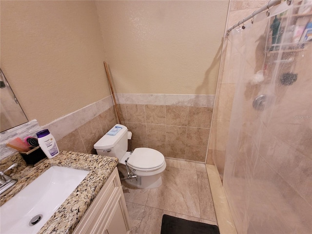 bathroom with curtained shower, vanity, tile walls, and toilet