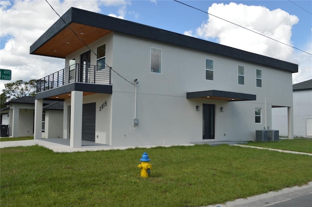 view of front of house featuring a garage, a front yard, a balcony, and stucco siding