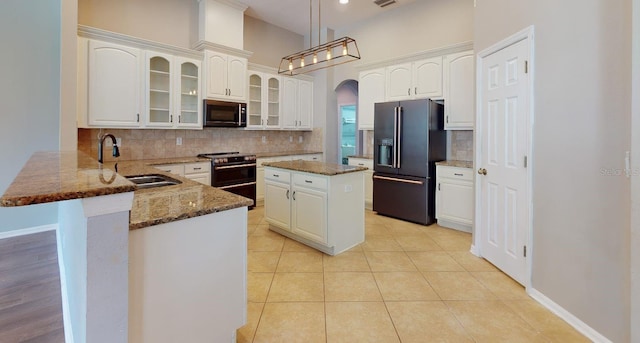 kitchen featuring a kitchen island, high end black fridge, kitchen peninsula, dark stone counters, and electric range oven