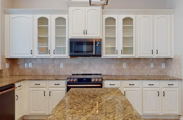 kitchen with light stone countertops, white cabinets, dishwasher, high quality range, and decorative backsplash