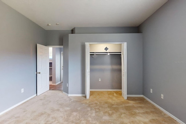 unfurnished bedroom with light carpet and a closet