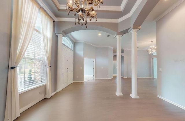 entrance foyer with crown molding, hardwood / wood-style flooring, a chandelier, and ornate columns