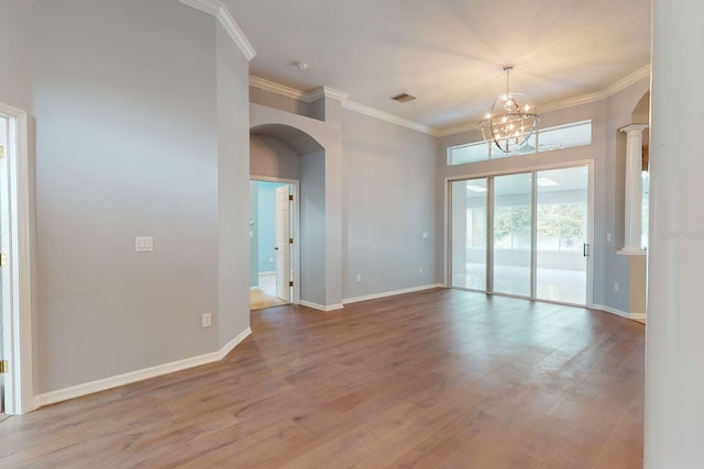 spare room with crown molding, hardwood / wood-style floors, decorative columns, and a chandelier