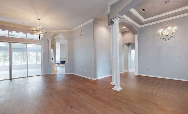 empty room with wood-type flooring, decorative columns, a chandelier, and ornamental molding