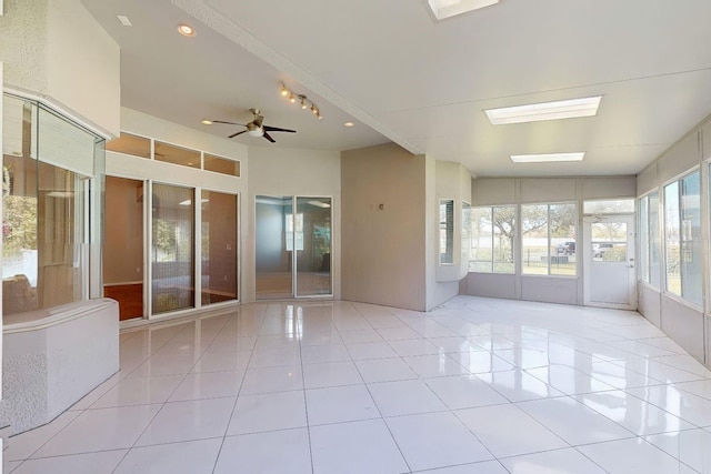 spare room with ceiling fan, a skylight, and light tile patterned flooring