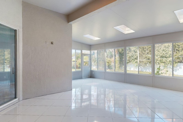 unfurnished sunroom featuring beam ceiling and a skylight