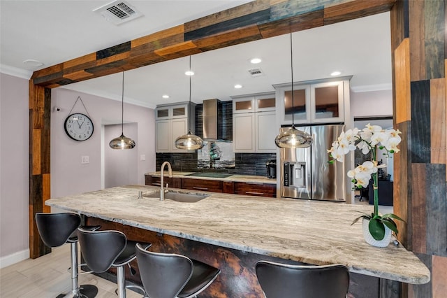 kitchen with decorative backsplash, stainless steel fridge, sink, and a breakfast bar area