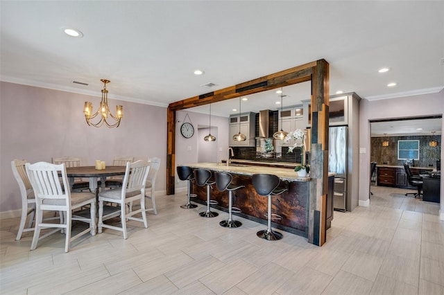 kitchen with pendant lighting, light stone counters, backsplash, and a breakfast bar area