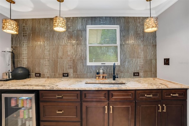 bar with dark brown cabinets, decorative light fixtures, ornamental molding, and sink