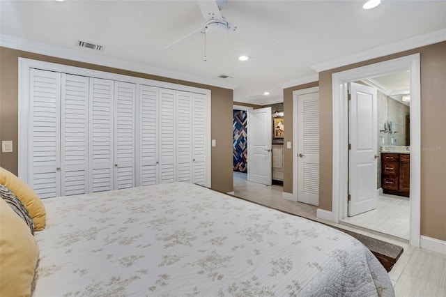 bedroom with ensuite bath, ceiling fan, multiple closets, ornamental molding, and light wood-type flooring