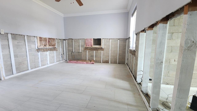 unfurnished room with ceiling fan, crown molding, a high ceiling, and tile walls