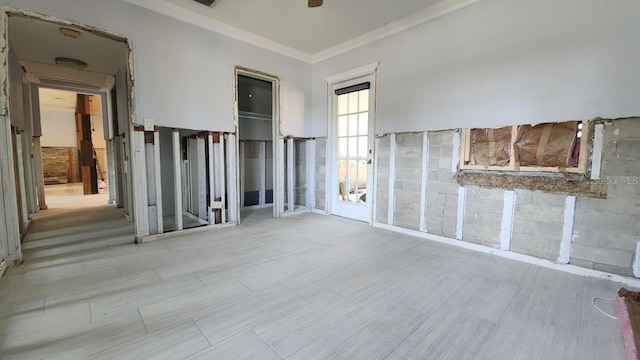 spare room featuring crown molding, ceiling fan, and tile walls