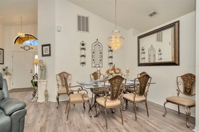 dining room featuring a chandelier, vaulted ceiling, and light hardwood / wood-style floors