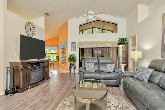 living room with ceiling fan, light hardwood / wood-style flooring, and high vaulted ceiling