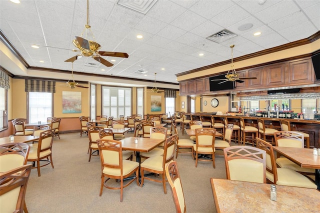 carpeted dining room with ceiling fan and crown molding