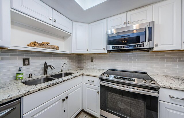 kitchen with white cabinets, decorative backsplash, and stainless steel appliances