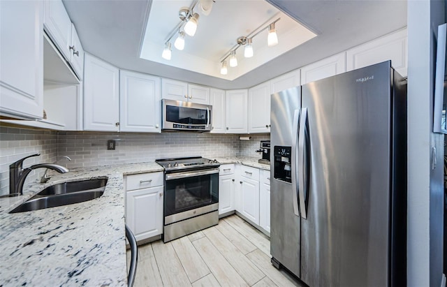 kitchen with stainless steel appliances, light stone countertops, white cabinets, and a raised ceiling