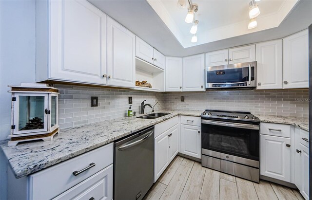 kitchen with tasteful backsplash, white cabinets, sink, and stainless steel appliances