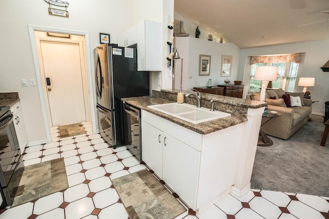 kitchen featuring lofted ceiling, sink, appliances with stainless steel finishes, white cabinetry, and kitchen peninsula