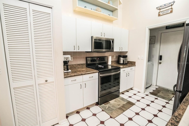 kitchen featuring dark stone countertops, a towering ceiling, stainless steel appliances, tasteful backsplash, and white cabinets