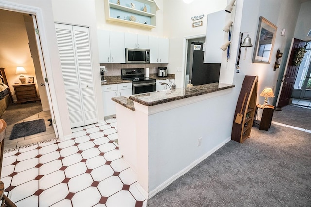 kitchen with stainless steel appliances, kitchen peninsula, and white cabinets