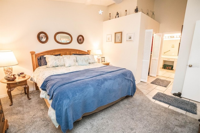 tiled bedroom featuring ensuite bath and a high ceiling