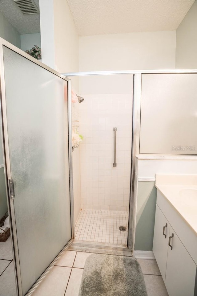 bathroom featuring vanity, an enclosed shower, tile patterned flooring, and a textured ceiling