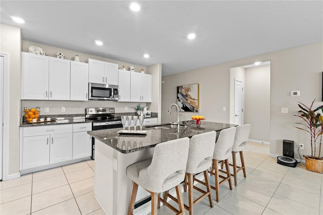 kitchen with sink, stainless steel appliances, a kitchen breakfast bar, an island with sink, and white cabinets