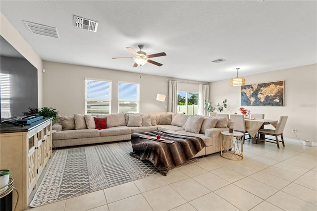 tiled living room with ceiling fan and a textured ceiling