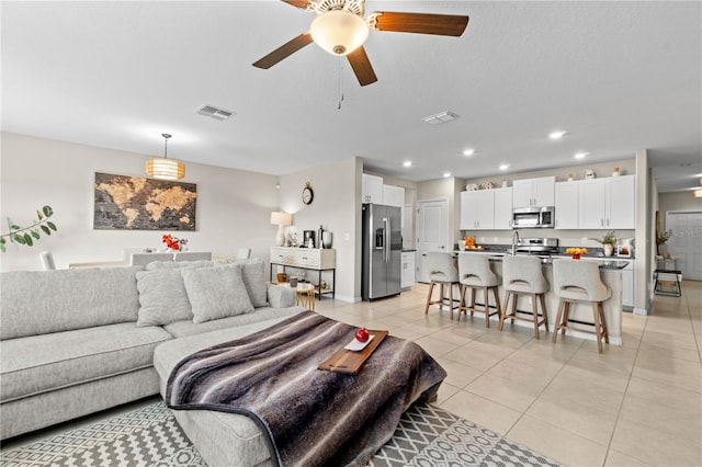 tiled living room featuring ceiling fan and sink