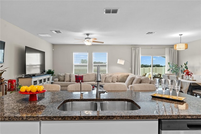 kitchen with pendant lighting, a center island with sink, plenty of natural light, and dark stone countertops