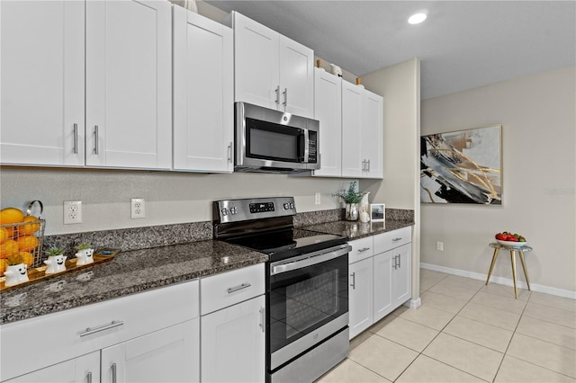 kitchen featuring white cabinets, dark stone countertops, light tile patterned floors, and stainless steel appliances