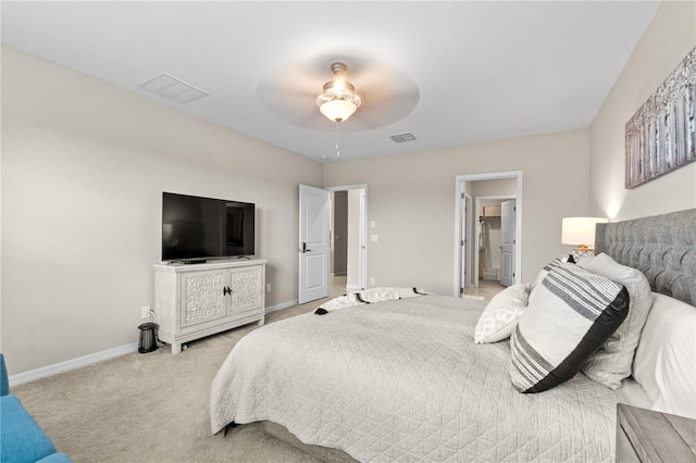 bedroom with connected bathroom, light colored carpet, and ceiling fan