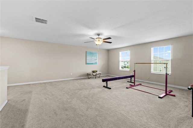 exercise area with ceiling fan and light colored carpet