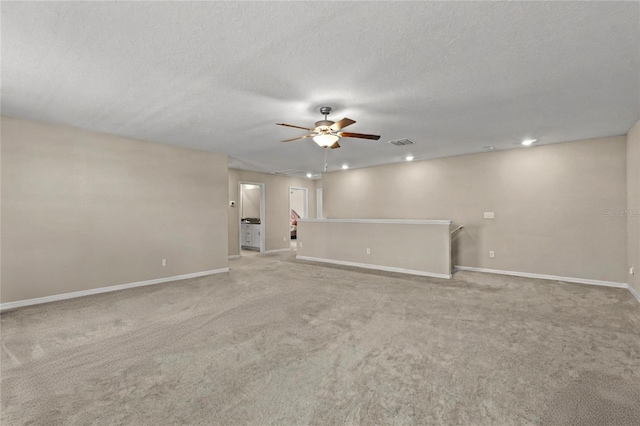 empty room with a textured ceiling, ceiling fan, and light carpet