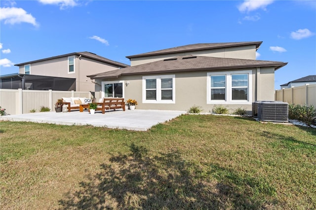 back of property with central AC unit, a patio area, and a yard