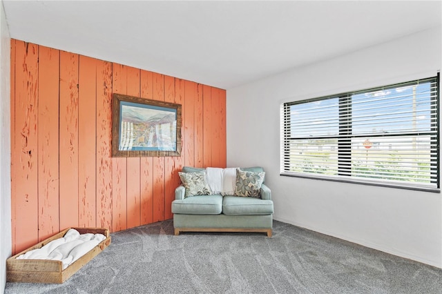 living area with carpet flooring and wooden walls