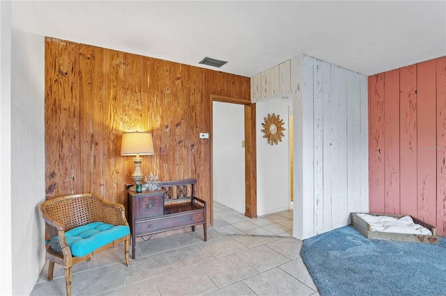 sitting room featuring wood walls and light tile patterned floors