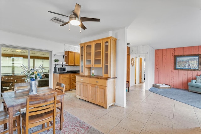 kitchen featuring wood walls, decorative backsplash, light tile patterned floors, and ceiling fan