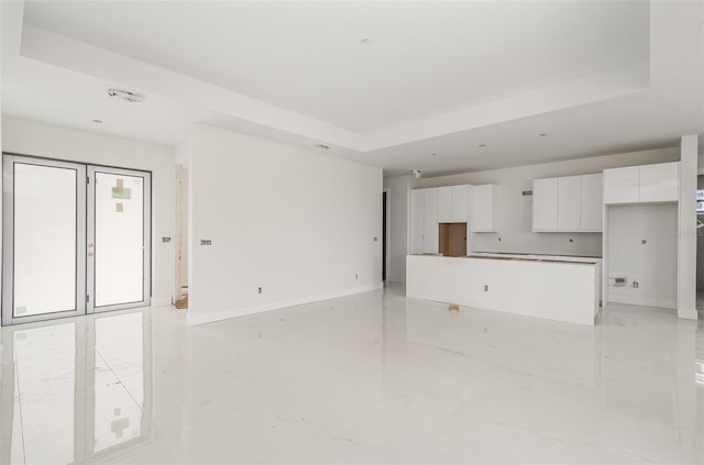 unfurnished living room featuring a raised ceiling