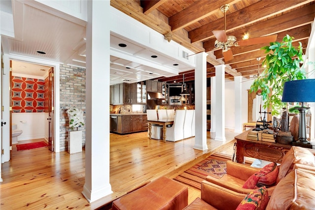 living room with an inviting chandelier, light wood-type flooring, ornamental molding, beamed ceiling, and decorative columns