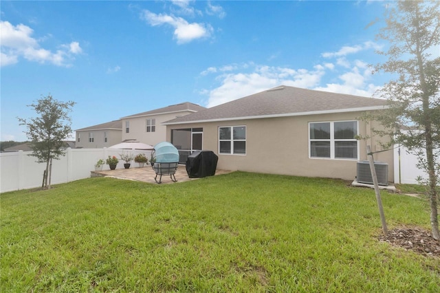 rear view of property with a lawn, cooling unit, and a patio area