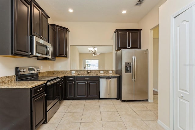 kitchen featuring stainless steel appliances, light stone countertops, a notable chandelier, sink, and dark brown cabinets