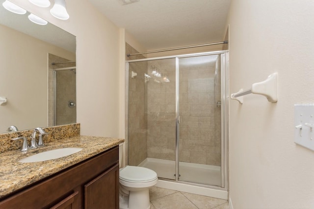 bathroom with toilet, tile patterned flooring, a shower with shower door, and vanity