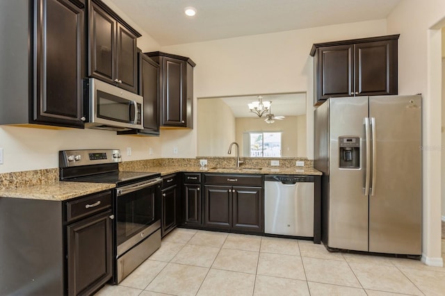 kitchen featuring pendant lighting, sink, stainless steel appliances, light stone countertops, and dark brown cabinets