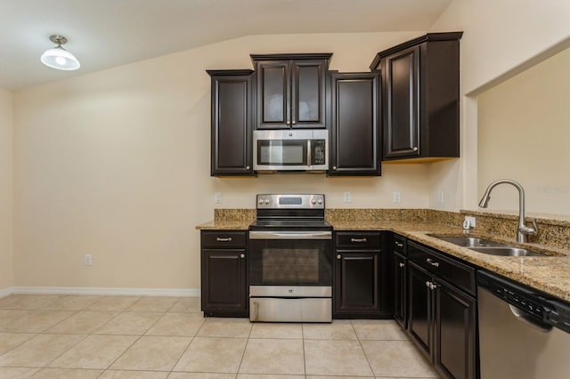 kitchen with appliances with stainless steel finishes, lofted ceiling, sink, light tile patterned floors, and light stone countertops